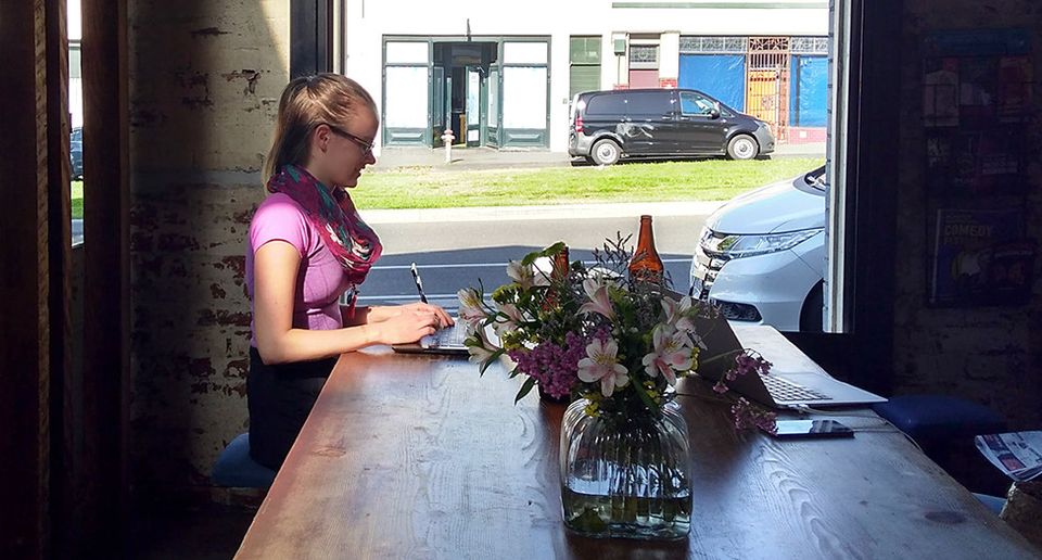 Graphic designer working on her laptop in a sunny café.